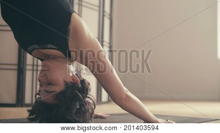 A young woman performing yoga-asanas in the hall. Artha mukha svanasana.