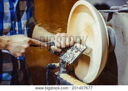 man turning a wooden plate on a lathe