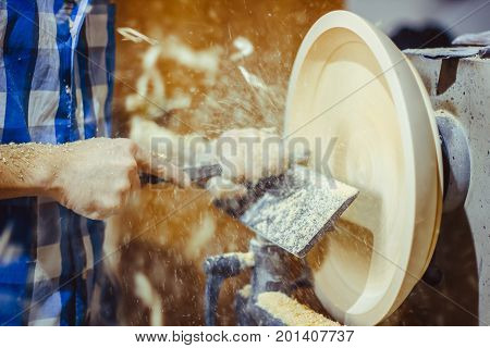 man turning a wooden plate on a lathe