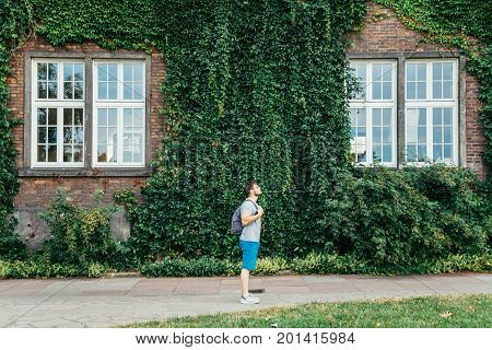 man listening music building in ivy on background summer day