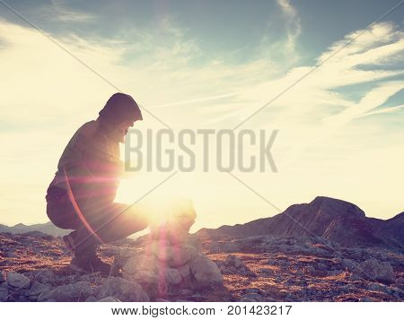 Alone Adult Man Is Stocking Stone To Pyramid.alps Mountain Summit, Evening Sun At Horizon.