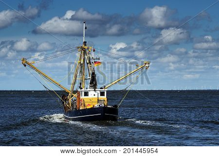 crabs or shrimp fishing boat on the North Sea under a blue sky with clouds copy space