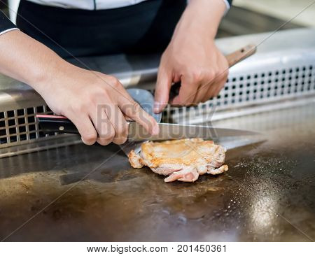 Hand Of Chef Cooking Chicken Steak On Hot Pan In Front Of Customers.