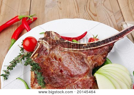 cibo di carne: arrosto nervatura sul piatto bianco con pepe timo e pomodoro sul tavolo di legno
