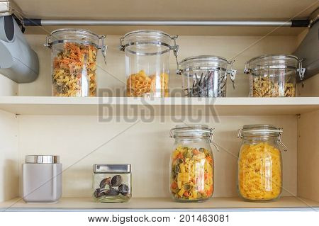 Kitchen cabinet with opened fronts with kitchen bench shelves with various food ingredients on white background