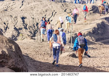 Unidentified tourist walking through on the craters of Gunung Bromo and Sumeru volcanoes in Java Indonesia