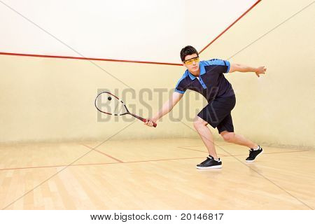 Ein Squash-Spieler-Heizng eine Kugel in einen Squash-court