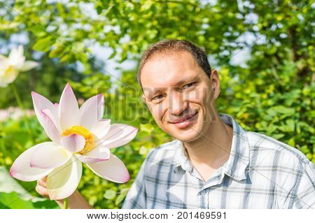 Portrait Closeup Of Young Man Smiling Holding Bright White And Pink Lotus Flower With Yellow Seedpod