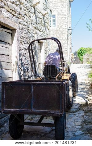 ULCINJ, MONTENEGRO - JULY 27, 2017: Local resident drives a small tractor through narrow old street in Stari Grad of Ulcinj, Montenegro.