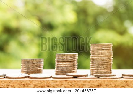 tep of coins stacks with nature background money saving and investment or family planning concept over sun flare silhouette tone.