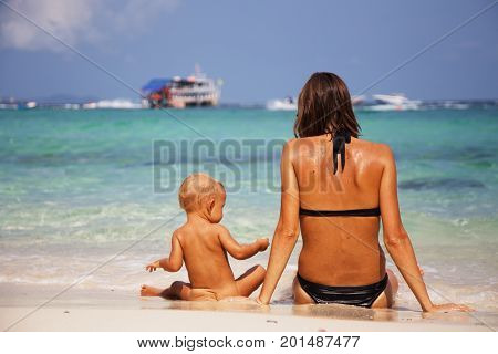 Happy mom and her adorable little daughter during summer vacation on the tropical beach