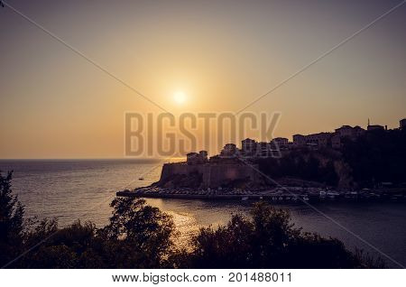 Beautiful sunset view on sea and Stadi Grad - old town of Ulcinj at twilight scene. Coast of Adriatic sea. Montenegro.