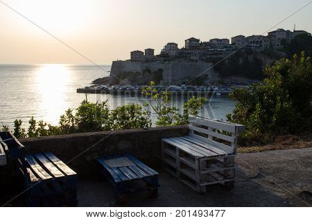 Cozy bar with the beautiful sunset view on sea and Stadi Grad - old town of Ulcinj at twilight scene. Coast of Adriatic sea. Montenegro.