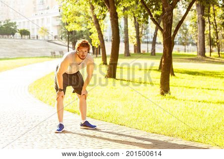 Pause in running. Redhead young adult man tired after running. Outdoor