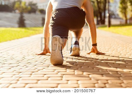Runner in park. Young athletic man jogging at morning. Low star. Fitness model in crossfit exercise outdoors. Healthy lifestyle concept.