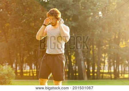 Young adult bearded sportsman listen a music in headphone. Outdoor shot