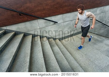 Running up on the stairs. Redhead athlete jogging on the stairs and left park. Outdoor
