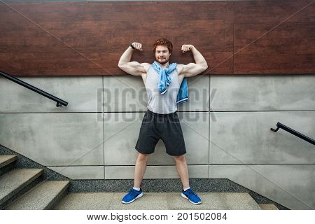 Poses as mister olympya. Show bicep. Smiling and looking at camera