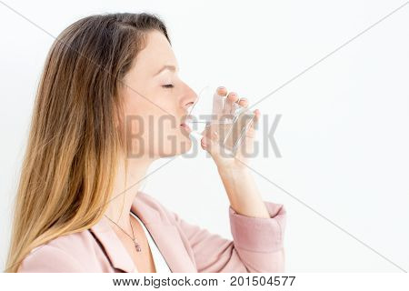 Side view of young Caucasian businesswoman wearing jacket enjoying drinking water