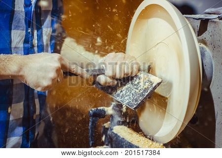 man turning a wooden plate on a lathe