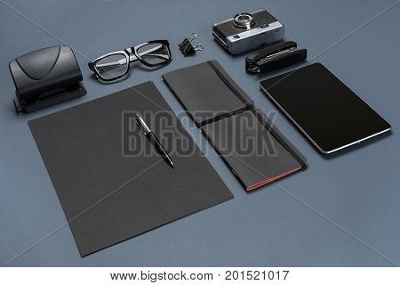 A set of black office accessories, glasses, old camera and tablet on gray background. Flat lay. Still life. Mock-up