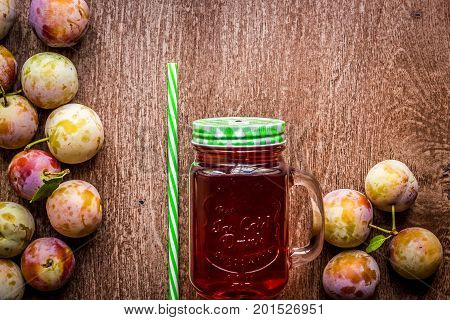 Glass with fresh Plum Juice on vintage wooden background. Top view. Copy space. Still life. Flat lay