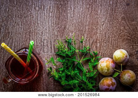 Glass with fresh Plum Juice and green mint on vintage wooden background. Top view. Copy space. Still life. Flat lay