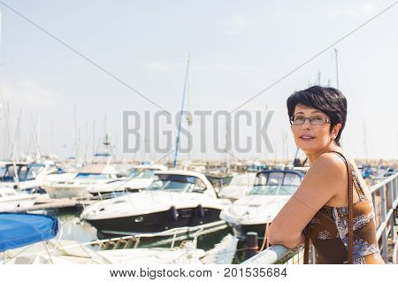 Leisure woman on holiday near yacht and sailboats marina resort town. Luxury lifestyle