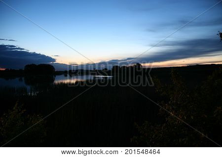 A calm pond surface with wood in nice sunrise with dawn and fog.