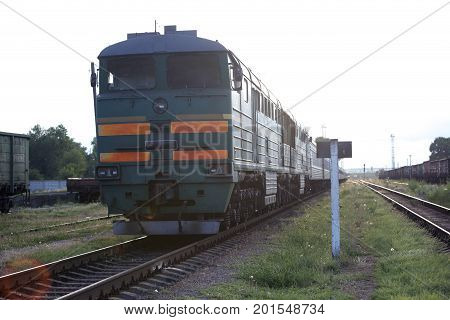 The old green locomotive stands on rails outside the city.
