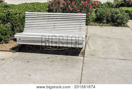 White bench in the street on a sunny summer day.