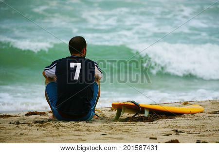 surfer waiting for waves on beach with surfboard