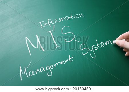 Female hand writing management abbreviation MIS with its full form on chalk board