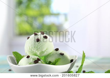 Bowl with delicious mint chocolate chip ice cream on light blurred background