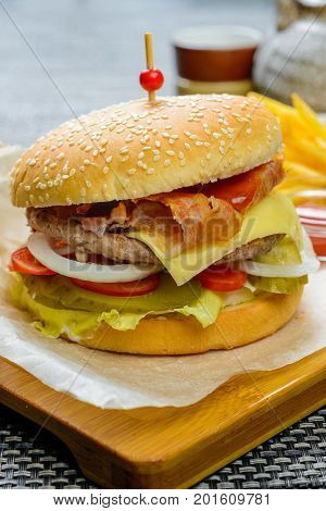 Cheese burger with bakon garnished with sauces and french fries