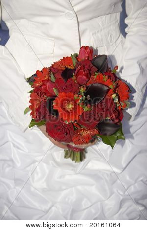 panna młoda w białe pasujące kurtka i głęboki czerwony bukiet