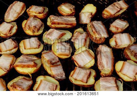 Big Slice Of Village-Style Potatoes On Hot BBQ Charcoal Grill. Flames of Fire In The Background. Tasty Snack For Outdoor Summer Barbecue Party Or Picnic.