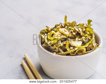 Close up view of kelp seaweed salad with sesame seeds on gray concrete background. Copy space.