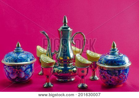 Gold ingot Gold jug Tea glass benjarong on red background.