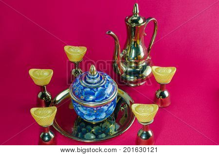 Gold ingot Gold jug Tea glass benjarong on red background.