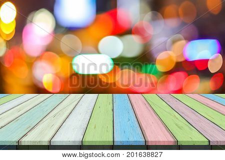 Empty old painted color wooden table or plank with bokeh of light from road or street with city tower on background for product display.