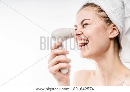 Young Happy woman with funny face use an electric brush for deeply clean on the nose, laughing and enjoy expression.Isolated on white