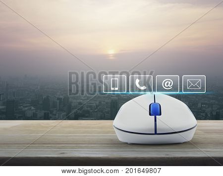Telephone mobile phone at and email buttons with wireless computer mouse on wooden table over modern city tower at sunset vintage style Customer support concept