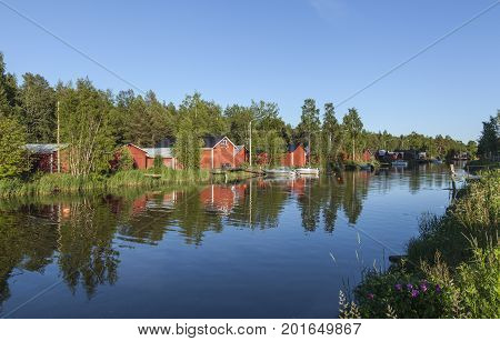 KOKKOLA, FINLAND ON JULY 07. View of a channel, red wooden boathouses by the seaside. Flowers this side on July 07, 2017 in Kokkola, Finland. Evening and bright sunshine. Editorial use.
