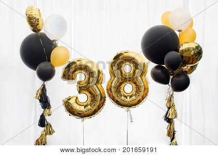 Decoration for birthday, anniversary, celebration of the thirtieth eight anniversary, white background, gold and black balloons with tassels