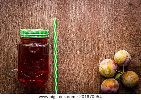 Glass with fresh Plum Juice on vintage wooden background. Top view. Copy space. Still life. Flat lay