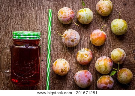 Glass with fresh Plum Juice on vintage wooden background. Top view. Copy space. Still life. Flat lay