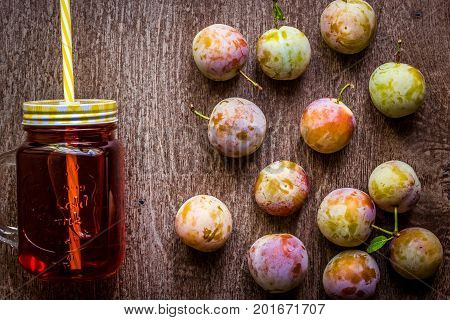Glass with fresh Plum Juice on vintage wooden background. Top view. Copy space. Still life. Flat lay