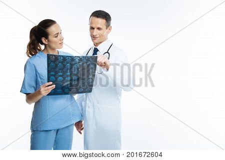 Best team mates. Friendly looking colleagues in a medical attire standing next to each other and talking over a patient diagnosis while looking at an x ray scan image.