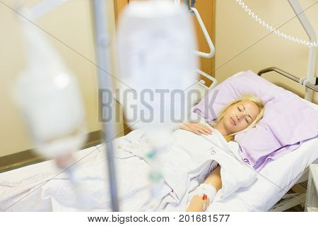 Bedridden female patient lying in hospital bed, recovering after surgery.
